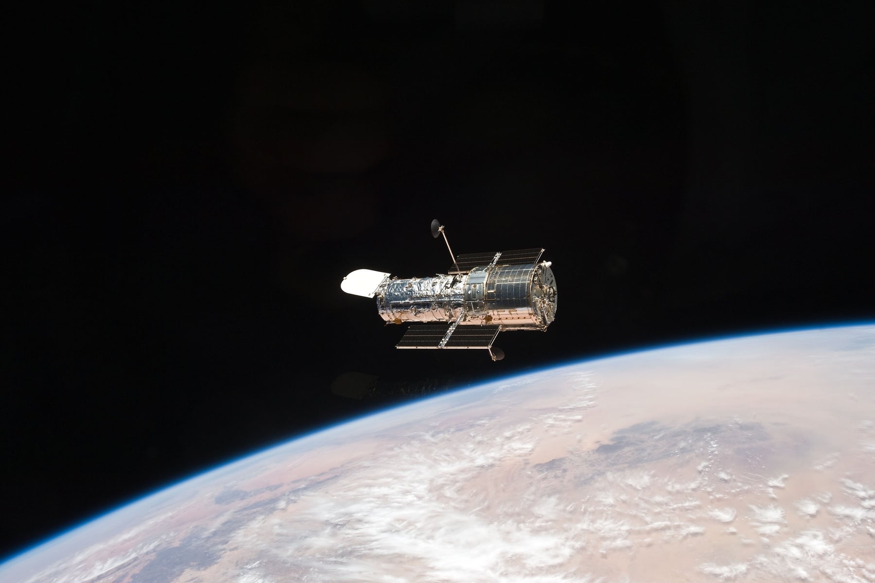 When Hubble swings from one galaxy to another, engineers fire no thrusters—Hubble has none. They change the speeds of four internal reaction wheels, making the observatory rotate the opposite way, while magnetic bars push against Earth’s field to bleed off excess momentum: a propellant-free steering system used since 1990.